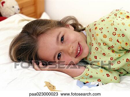 Young girl laying on bed smiling, portrait. View Large Photo Image Stock Image - Young girl laying on bed smiling, portrait.. Fotosearch