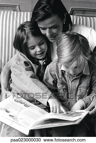 Young woman holding two children on lap, looking at book, b&w View Large Photo Image Stock Image - Young woman holding two children on lap, looking at book, b&w. Fotosearch
