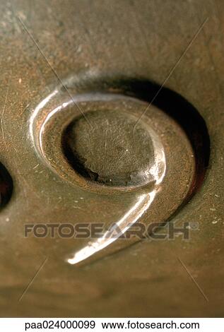 Stock Photo - 9 text, embossed in bronze-colored surface. Fotosearch
