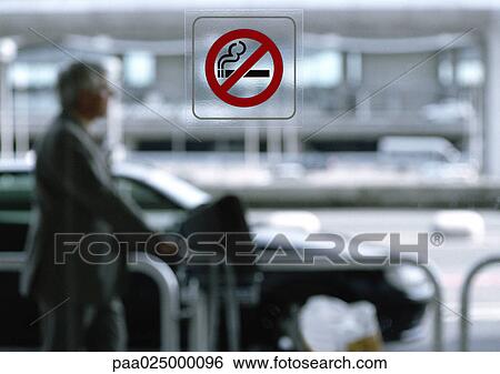 Man standing outside, no smoking sign on window in foreground View Large Photo Image Stock Photograph - Man standing outside, no smoking sign on window in foreground. Fotosearch