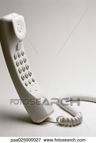 Stock Photo - White telephone handset standing on end, close-up. Fotosearch