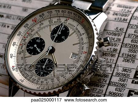 Wristwatch on top of stock report, extreme close-up View Large Photo Image Stock Photo - Wristwatch on top of stock report, extreme close-up. Fotosearch