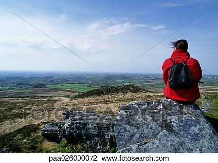 France, Brittany, hiker sitting on rock, looking out over landscape, rear view. View Large Photo Image Stock Image - France, Brittany, hiker sitting on rock, looking out over landscape, rear view.. Fotosearch
