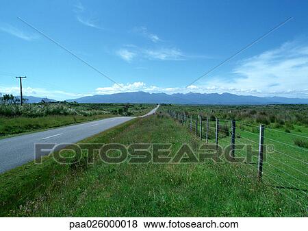 New Zealand, road going through grassy rural area, mountain range in distance View Large Photo Image Stock Photo - New Zealand, road going through grassy rural area, mountain range in distance. Fotosearch