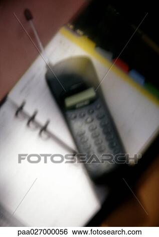 Cell phone on open agenda, close-up, blurred View Large Photo Image Stock Photograph - Cell phone on open agenda, close-up, blurred. Fotosearch