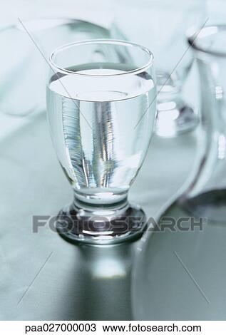 Glass of water with carafe blurred in foreground View Large Photo Image Stock Image - Glass of water with carafe blurred in foreground. Fotosearch