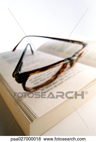 Stock Photo - Glasses laying on open book, close-up. Fotosearch
