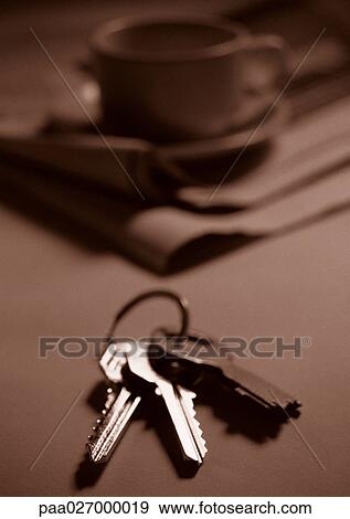 Keys on table, cup and saucer on newspaper in background View Large Photo Image Stock Photo - Keys on table, cup and saucer on newspaper in background. Fotosearch