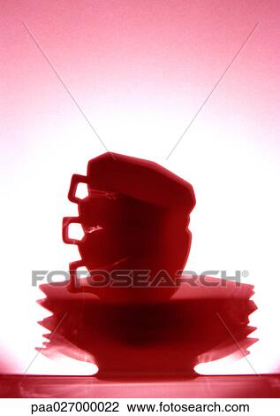 Stock Image - Stack of cups and saucers, red-toned. Fotosearch