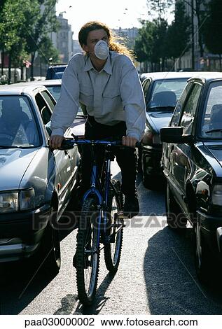 Person riding bike in between cars with pollution mask on. View Large Photo Image Stock Image - Person riding bike in between cars with pollution mask on.. Fotosearch