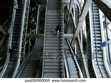 Woman walking down steps in between escalators. View Large Photo Image Stock Photo - Woman walking down steps in between escalators.. Fotosearch