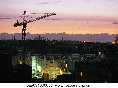 Stock Photography - Crane above rooftops at sunset. Fotosearch
