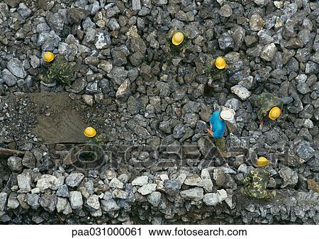 Stock Image - People on stones wearing hard hats and army fatigues, aerial view. Fotosearch