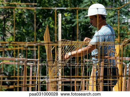 Stock Photo - Worker holding wire netting, side view. Fotosearch