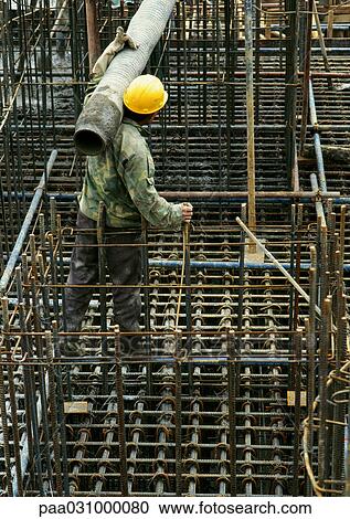 Stock Image - Worker wearing hard hat, holding pipe. Fotosearch