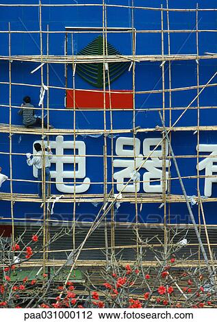 Stock Image - Workers on bamboo scaffolding. Fotosearch