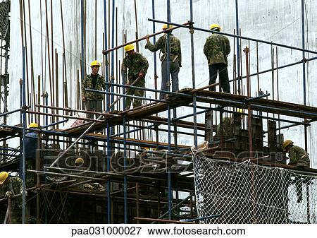 Workers with hard hats, standing on scaffolding View Large Photo Image Stock Photo - Workers with hard hats, standing on scaffolding. Fotosearch