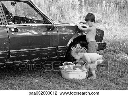 Stock Image - Boy and girl washing a car, b&w. Fotosearch