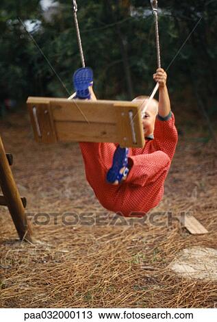 Stock Image - Boy hanging on swing. Fotosearch