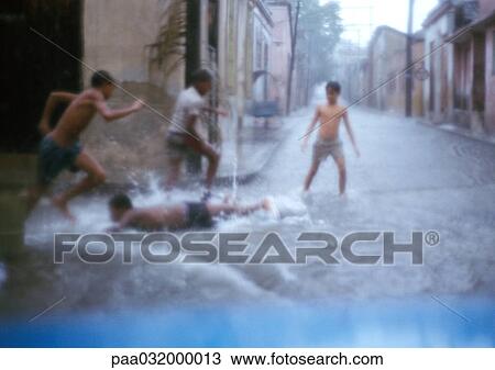Boys running in waterlogged street, one lying down on ground, blurred View Large Photo Image Stock Image - Boys running in waterlogged street, one lying down on ground, blurred. Fotosearch