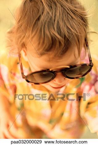 Stock Photo - Child wearing oversized sunglasses, elevated view. Fotosearch