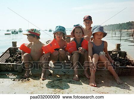 Stock Photo - Children sitting lined up, wearing water wings, on beach. Fotosearch