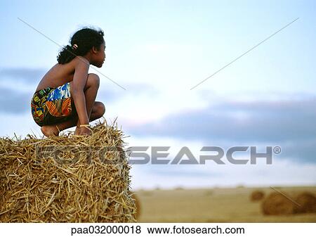 Girl crouching on haystack, side view View Large Photo Image Stock Photo - Girl crouching on haystack, side view. Fotosearch