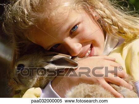 Stock Photography - Girl hugging rabbit, close-up. Fotosearch