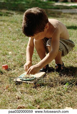 Little boy crouching on grass View Large Photo Image Stock Photo - Little boy crouching on grass. Fotosearch