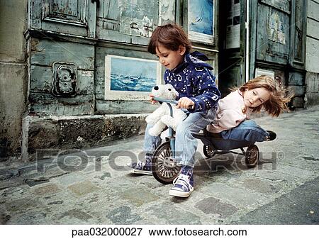 Stock Photo - Little boy riding tricycle with little girl on back. Fotosearch