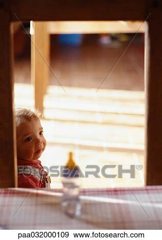 Stock Photo - Toddler in a room, blurred baby's bottle in foreground. Fotosearch