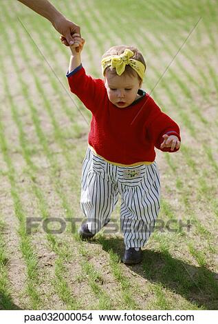 Picture - Toddler walking, holding adult hand. Fotosearch