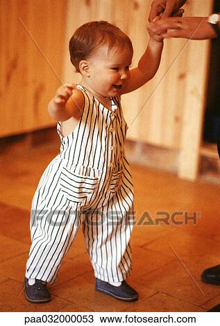 Stock Image - Toddler walking, holding adult hand. Fotosearch