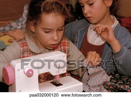 Two girls side by side, one using sewing machine View Large Photo Image Stock Image - Two girls side by side, one using sewing machine. Fotosearch