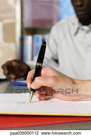 Stock Image - Hand holding pen, close-up. Fotosearch