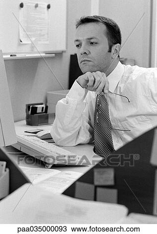 Stock Image - Man sitting at desk, elbow on table, b&w. Fotosearch