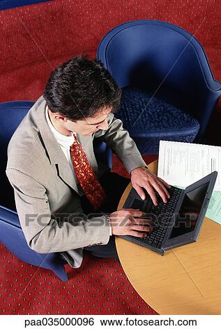 Man sitting at table, using laptop computer, elevated view View Large Photo Image Stock Photograph - Man sitting at table, using laptop computer, elevated view. Fotosearch
