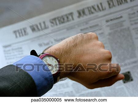 Stock Photography - Watch on wrist, newspaper in background. Fotosearch