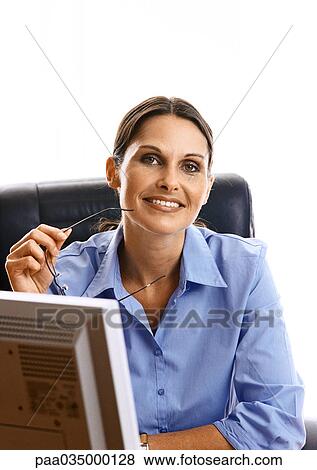 Woman sitting at desk, smiling, portrait View Large Photo Image Stock Photo - Woman sitting at desk, smiling, portrait. Fotosearch
