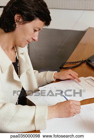 Woman sitting at desk, writing, side view View Large Photo Image Stock Photo - Woman sitting at desk, writing, side view. Fotosearch