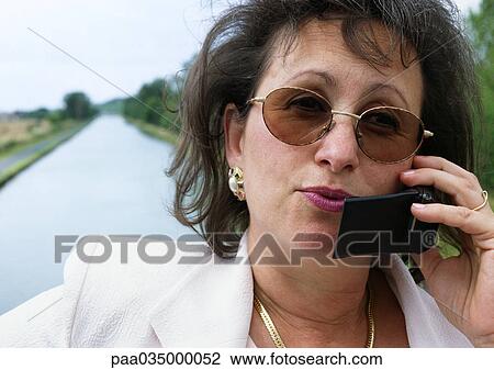 Stock Image - Woman using cell phone outside, close-up. Fotosearch