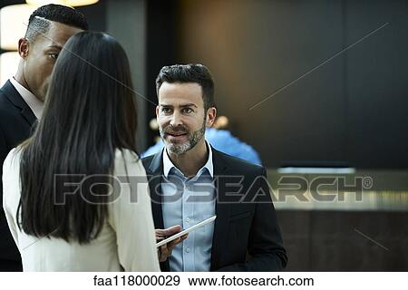 Business people discussing on digital tablet in hotel lobby View Large Photo Image Stock Photo - Business people discussing on digital tablet in hotel lobby. Fotosearch