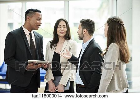 Business people standing and discussing in the hotel lobby View Large Photo Image Picture - Business people standing and discussing in the hotel lobby. Fotosearch