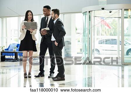 Business people standing and discussing in the hotel lobby View Large Photo Image Stock Image - Business people standing and discussing in the hotel lobby. Fotosearch