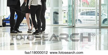 Stock Image - Business people standing and discussing in the hotel lobby. Fotosearch