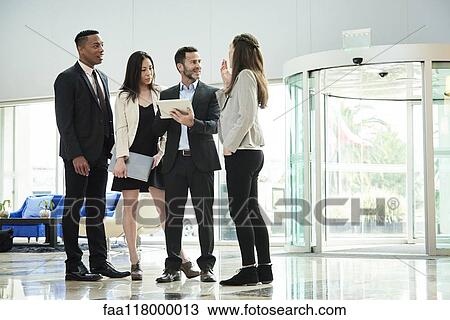 Business people standing and discussing in the hotel lobby View Large Photo Image Stock Image - Business people standing and discussing in the hotel lobby. Fotosearch