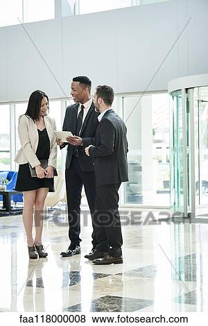 Stock Photo - Business people standing and discussing in the hotel lobby. Fotosearch