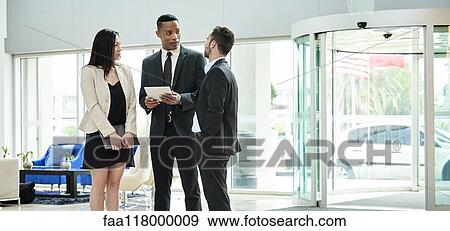 Stock Photo - Business people standing and discussing in the hotel lobby. Fotosearch