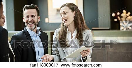 Business people standing and discussing in the hotel lobby View Large Photo Image Stock Photo - Business people standing and discussing in the hotel lobby. Fotosearch