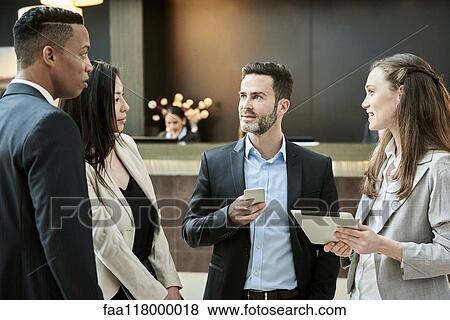 Business people standing and discussing in the hotel lobby View Large Photo Image Stock Photo - Business people standing and discussing in the hotel lobby. Fotosearch